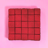 Raspberry & Dark Chocolate Brownie by Crumbs & Doilies, cut into squares with vibrant raspberry powder topping on pink background